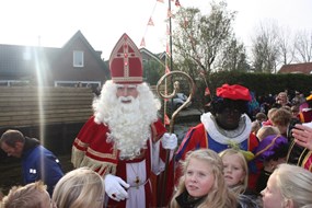 Sinterklaas uit de vlet en begroet de enthousiaste kinderen