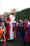 Sinterklaas loopt naar zijn rijtuig, begeleid door een aantal kinderen 