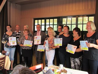 Alle Interne Cultuur Coordinatoren op de foto met de map en cheque